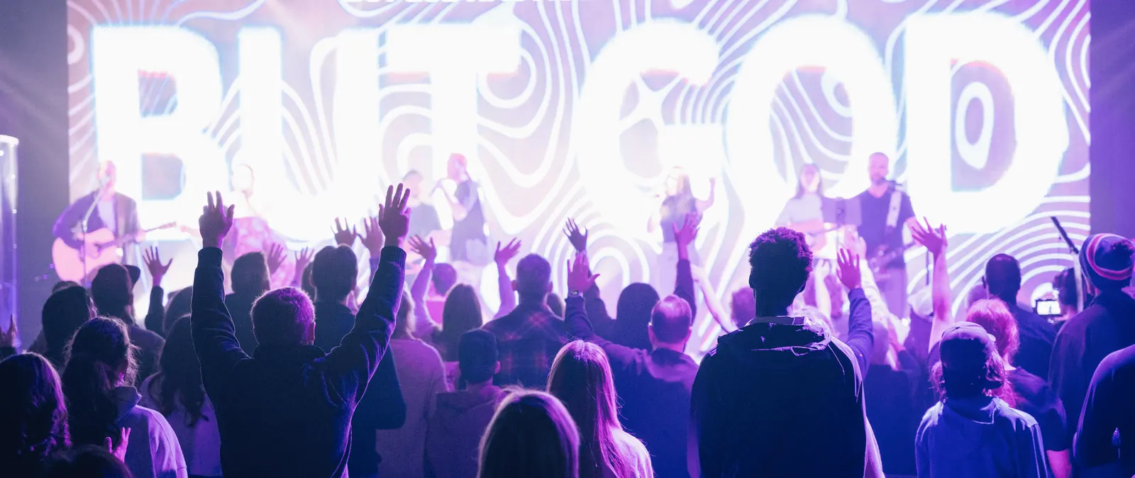 A crowd of people worshipping in an auditorium
