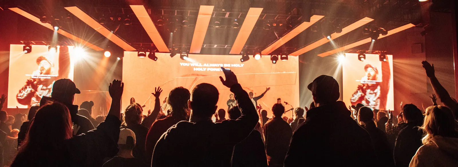 A crowd of people worshipping in an auditorium